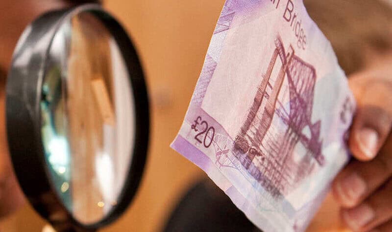 Looking at a Bank of Scotland £20 note with a magnifying glass