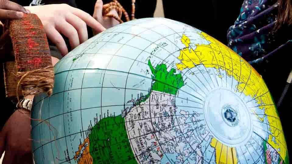 Inflatable Globe with fingers pointing to an island in the Pacific Ocean